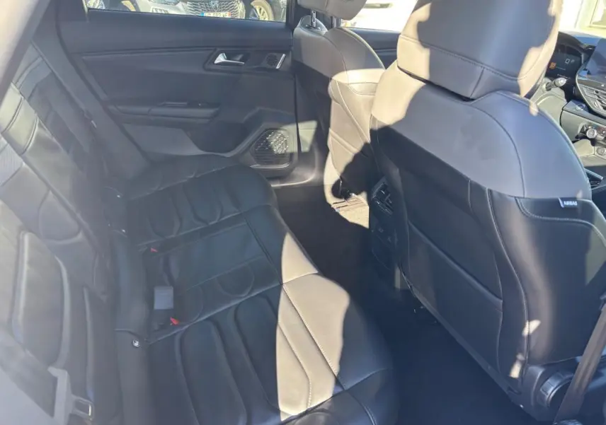 Vue intérieure arrière côté gauche d’une Citroën C5 X 2024 avec sièges en cuir noir et accoudoir central.