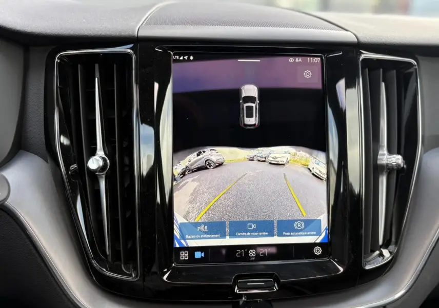 Écran tactile central affichant la caméra de recul du Volvo XC60 gris silver, entouré de deux aérateurs verticaux noirs.