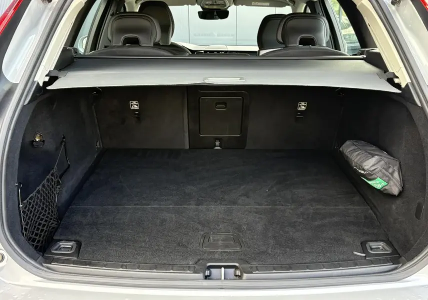 Coffre ouvert du Volvo XC60 gris silver, vue arrière montrant l’espace de chargement et la plage arrière rétractable.