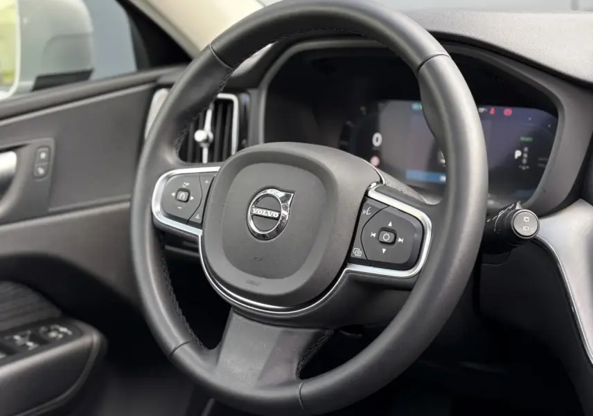 Volant simili-cuir noir de Volvo XC60 2024 vu de face, avec commandes intégrées et tableau de bord digital.
