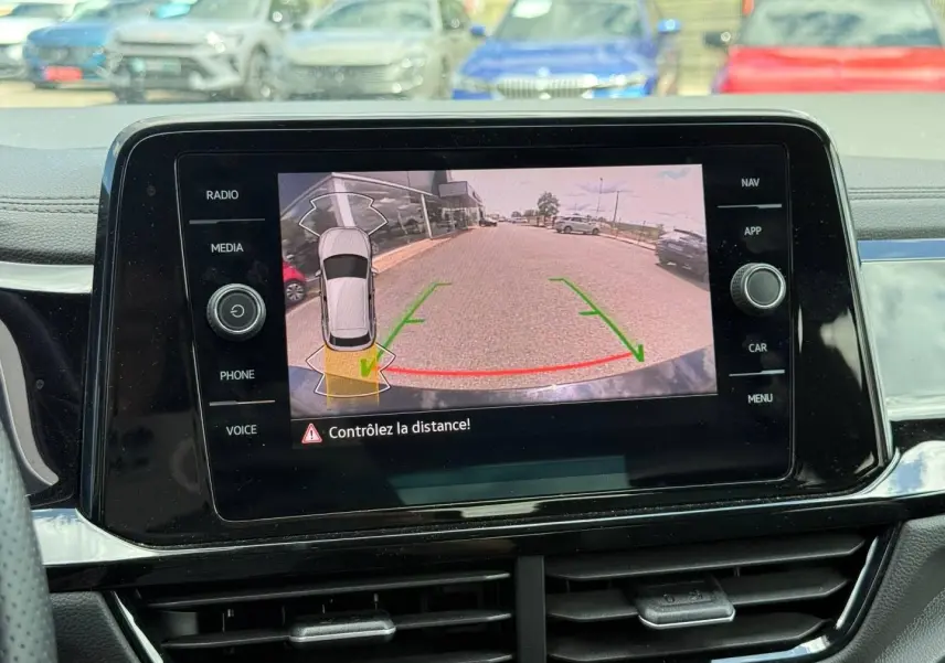 Vue intérieure sur l'écran tactile affichant la caméra de recul du Volkswagen T-Roc noir intense nacré, avec guidage de trajectoire.