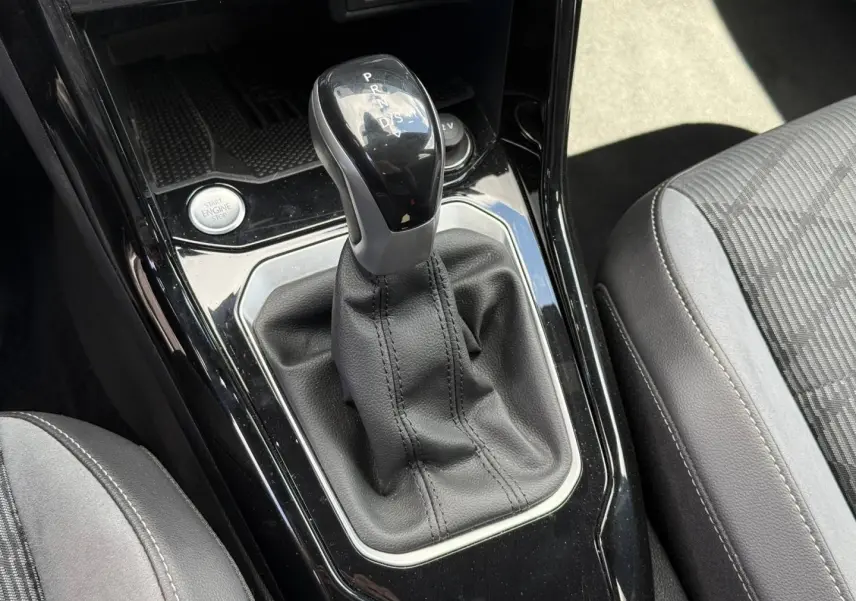 Le levier de vitesse automatique noir et cuir du Volkswagen T-Roc 1.5 TSI Evo2, vu en gros plan intérieur.