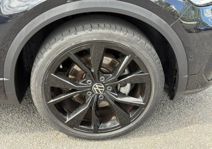 Gros plan sur la roue avant gauche noire avec jante alu noire du Volkswagen T-Roc Noir Intense nacrée 2025.
