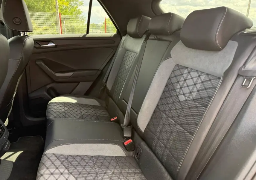 Vue latérale intérieure des sièges arrière du Volkswagen T-Roc 2025 avec sellerie mixte noire et grise à motifs géométriques.