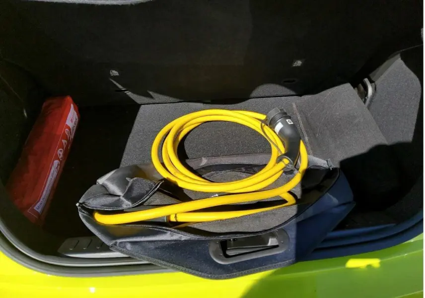 Coffre ouvert d’une FIAT 500 électrique jaune Acid avec câble de recharge jaune enroulé visible.