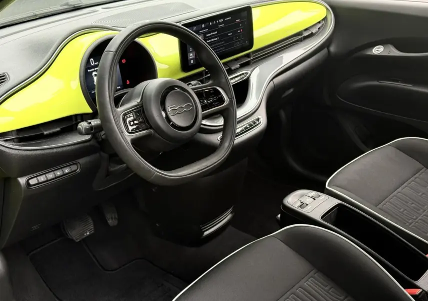 Intérieur avant droit de la Fiat 500 électrique 2024 avec tableau de bord jaune Acid et sièges tissu noir.