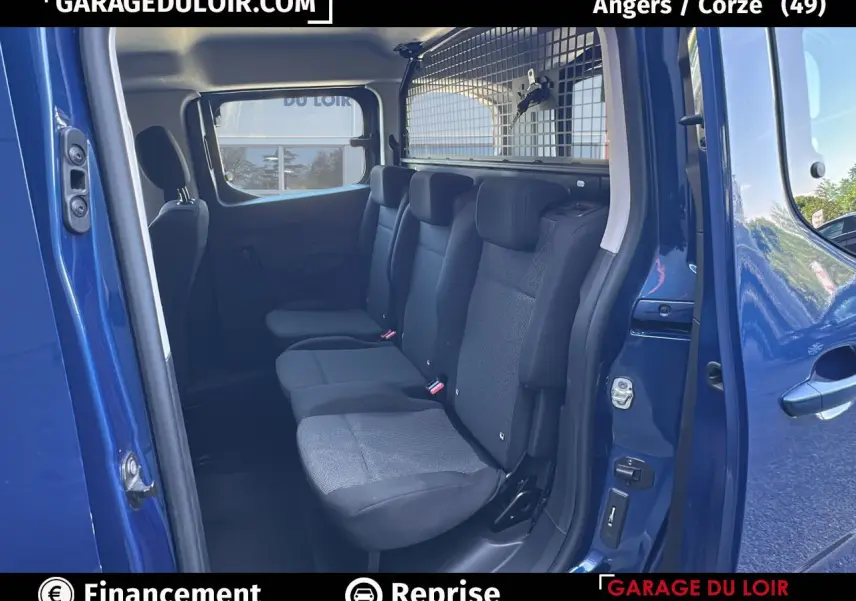 Vue intérieure côté droit sur la banquette arrière noire du Peugeot Rifter bleu avec cloison métallique de séparation