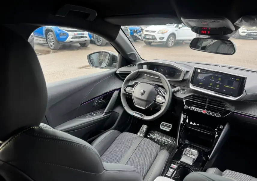 Vue intérieure avant droite du Peugeot 208 Hybrid 110 e-DCS6 GT gris, avec volant compact et écran tactile central.