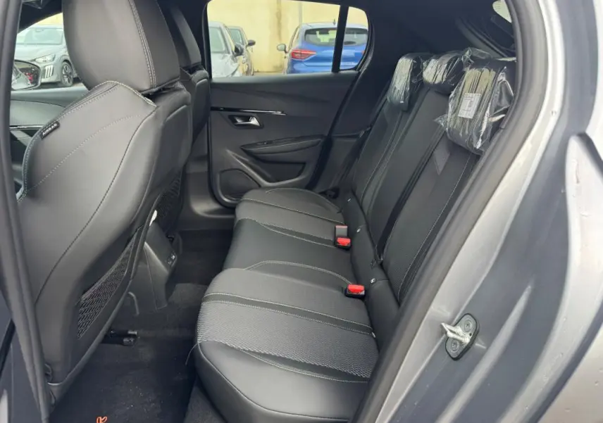 Vue latérale droite de l'intérieur arrière gris du Peugeot 208 Hybrid 110 e-DCS6 GT avec sièges en tissu et cuir.