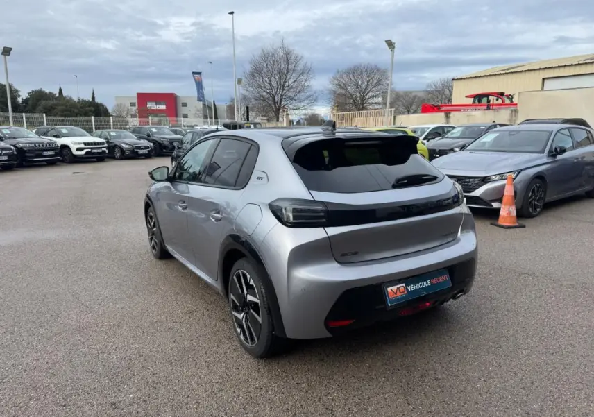 Vue 3/4 arrière droite d'une Peugeot 208 Hybrid 110 gris métallisé avec jantes alliage 17 pouces et vitres teintées.