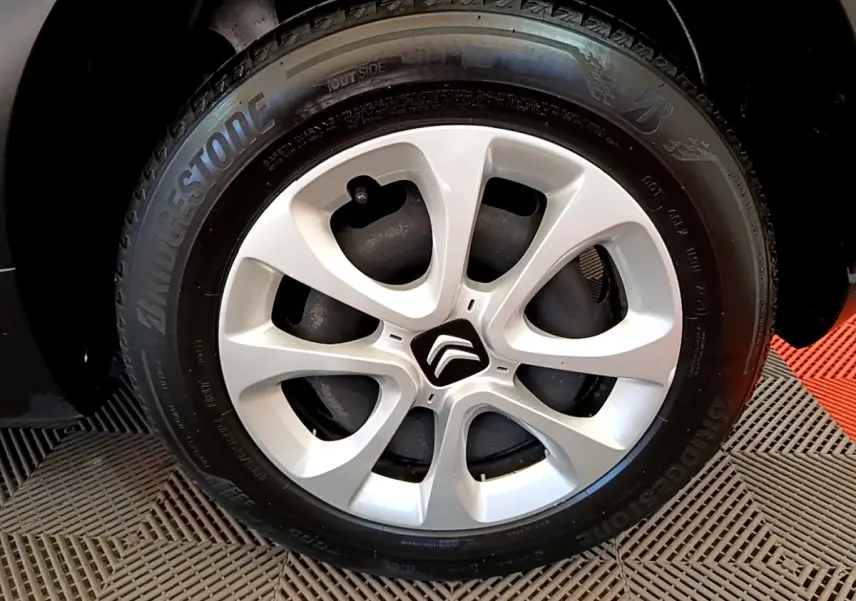 Gros plan sur la jante argentée avec logo Citroën au centre, pneu Bridgestone monté sur Citroën C3 blanche.