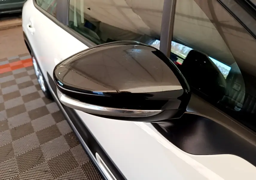 Rétroviseur noir avec clignotant intégré côté gauche d'une Citroën C3 blanche vue de profil rapproché.