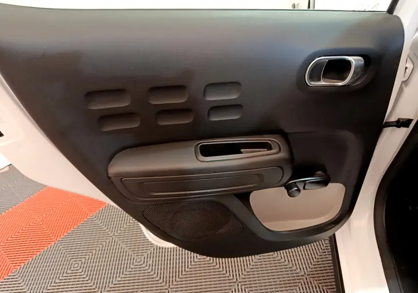 Vue rapprochée de la porte arrière gauche noire et blanche d’une Citroën C3 2022 avec poignée intégrée et manivelle de vitre.