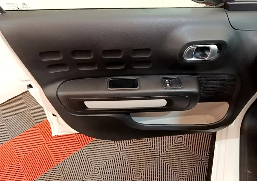 Vue rapprochée de la porte avant gauche blanche d'une Citroën C3 2022 avec panneau intérieur noir et poignée chromée.