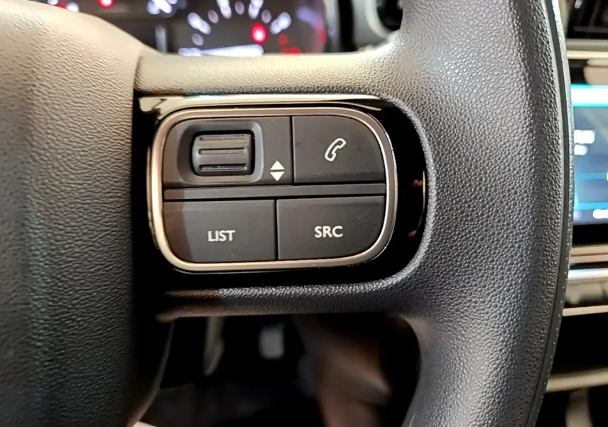 Gros plan sur les commandes gauche du volant noir de la Citroën C3 2022 avec boutons LIST, SRC et téléphone.