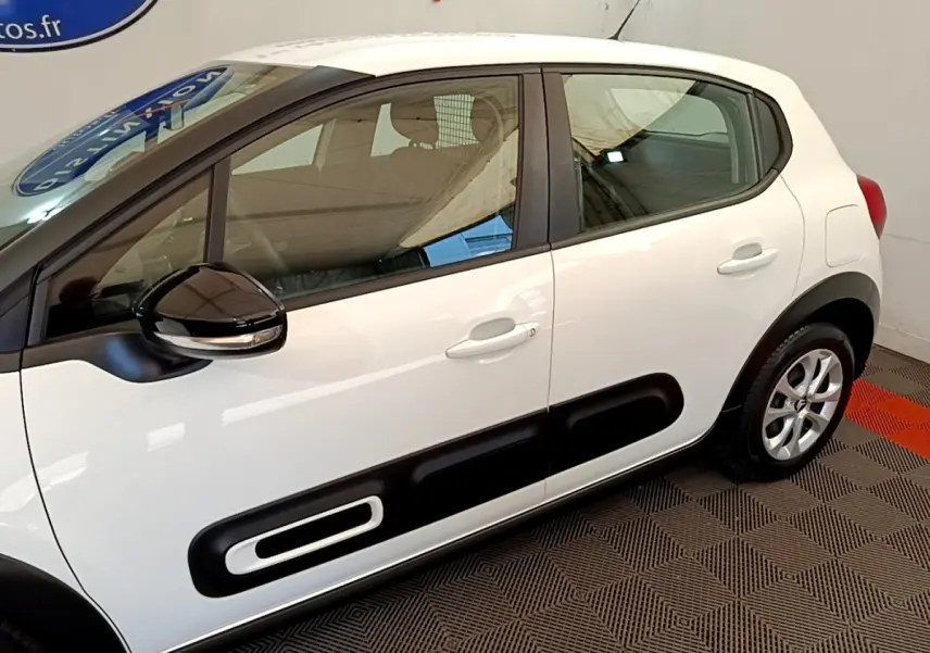 Vue latérale droite d'une Citroën C3 blanche 2022 avec protections noires caractéristiques sur les portières.