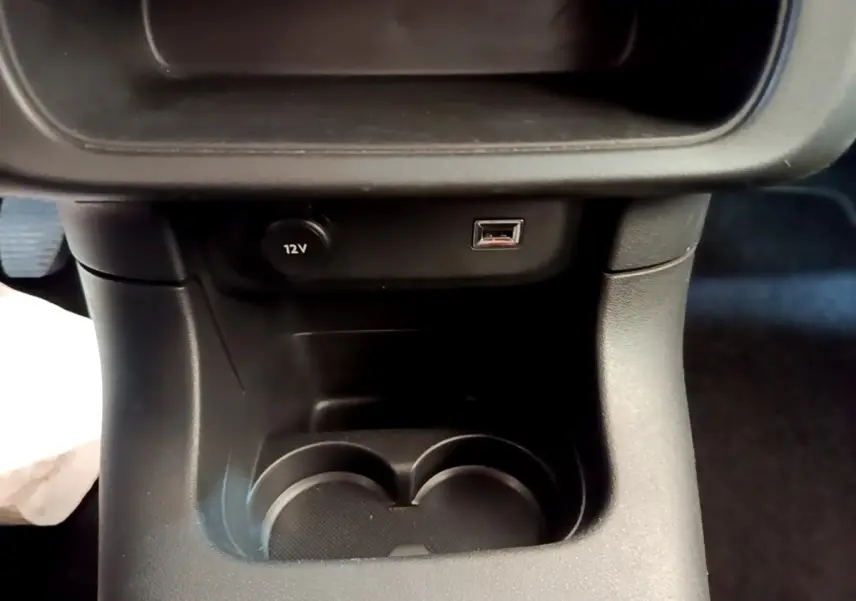 Gros plan sur la console centrale noire de la Citroën C3 avec prise 12V et port USB visible.