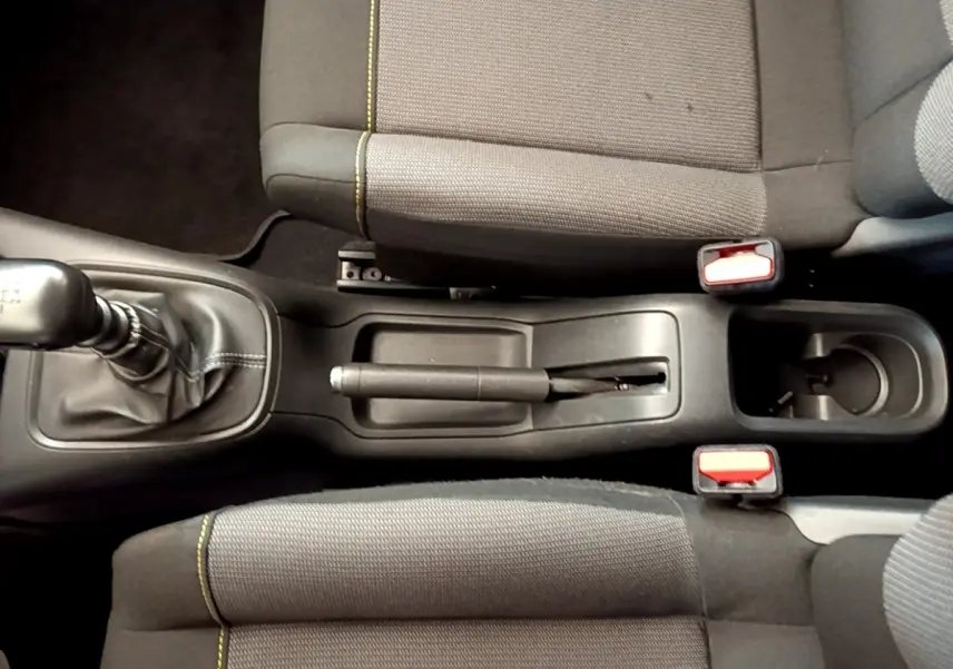 Vue plongeante sur la console centrale de la Citroën C3 avec levier de vitesse manuel et sièges tissu gris à surpiqûres jaunes.