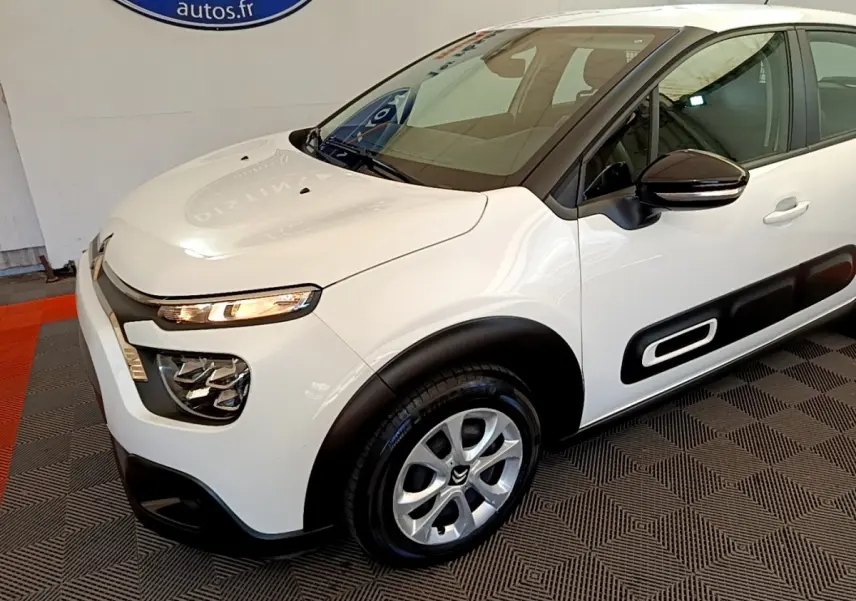 Vue 3/4 avant droite d'une Citroën C3 blanche avec protections latérales noires et jantes argentées.