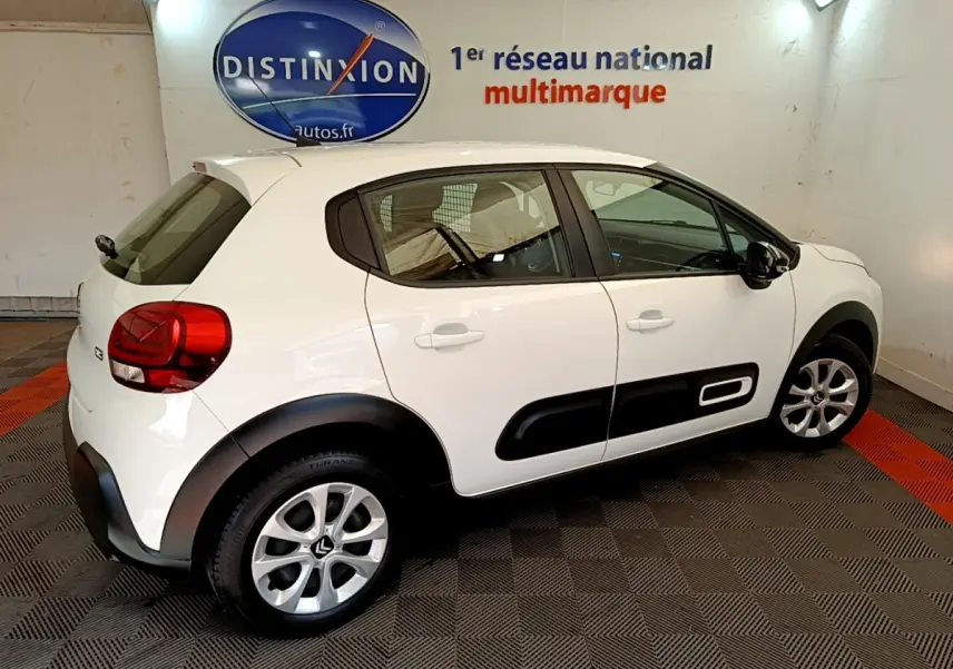 Vue latérale droite d'une Citroën C3 blanche 2022 avec protections noires sur les portières dans un showroom.