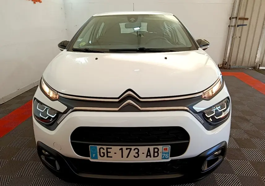Vue avant d'une Citroën C3 blanche 2022 avec phares LED et calandre noire dans un garage.
