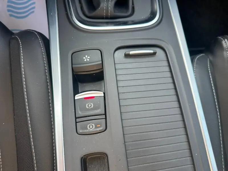 Vue rapprochée de la console centrale grise avec commandes électroniques du frein à main et arrêt auto sur Renault Mégane Break 2024.