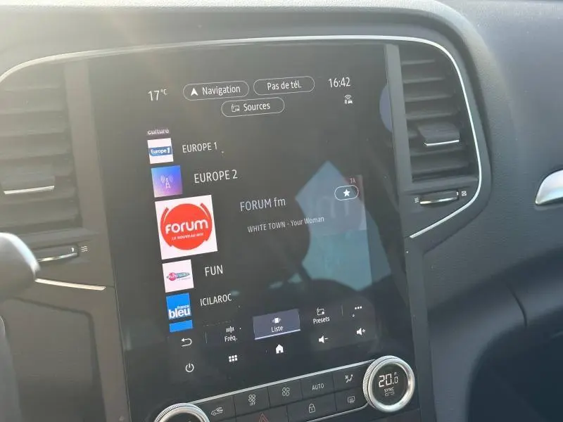 Écran tactile central affichant la radio dans l'habitacle gris d'une Renault Mégane Break 2024, vue de face.