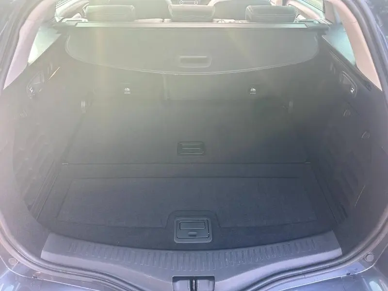 Coffre ouvert de la Renault Mégane Break gris Titanium 2024, montrant un espace de chargement propre et bien agencé.