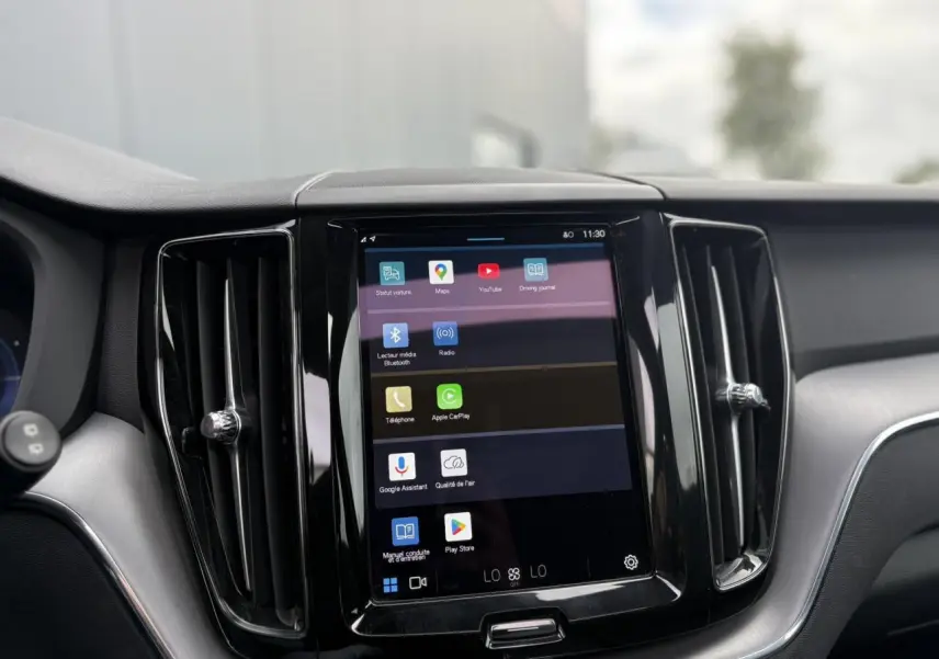 Vue rapprochée de l’écran tactile central 9 pouces du Volvo XC60 T6 AWD PHEV rouge, avec commandes multimédia et ventilation.