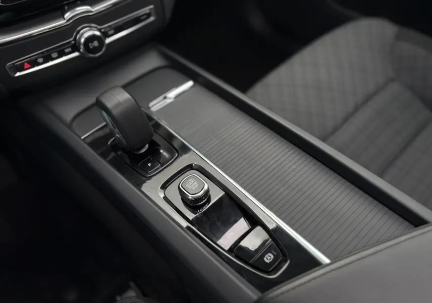 Vue rapprochée de la console centrale noire avec levier de vitesses et bouton start/stop du Volvo XC60 2024.