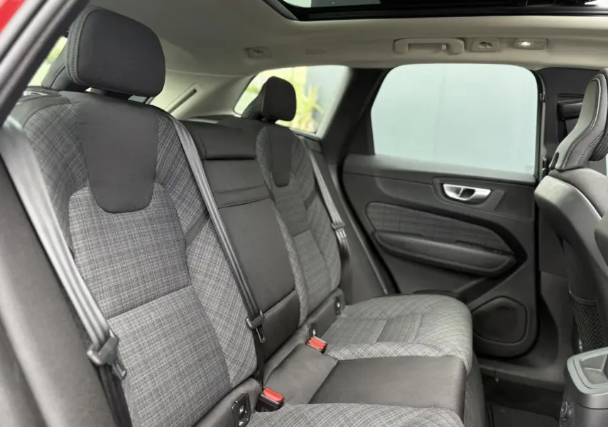 Vue intérieure arrière du Volvo XC60 2024, sièges en tissu gris à motif tartan avec ceinture de sécurité noire.