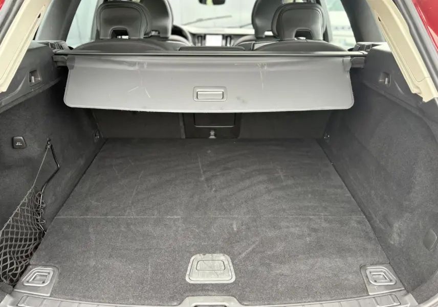 Coffre ouvert vu de l'arrière d'un Volvo XC60 rouge Fusion, avec cache-bagages et intérieur noir.