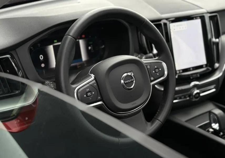 Vue rapprochée du volant noir et du tableau de bord digital du Volvo XC60 T6 AWD PHEV 2024.