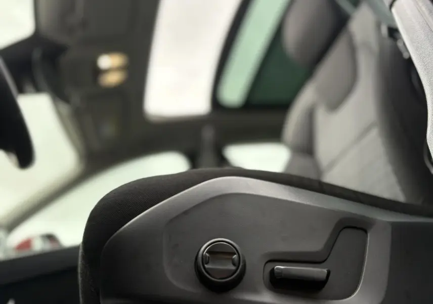 Détail des commandes de réglage électrique du siège avant gauche dans l'habitacle gris du Volvo XC60 2024.