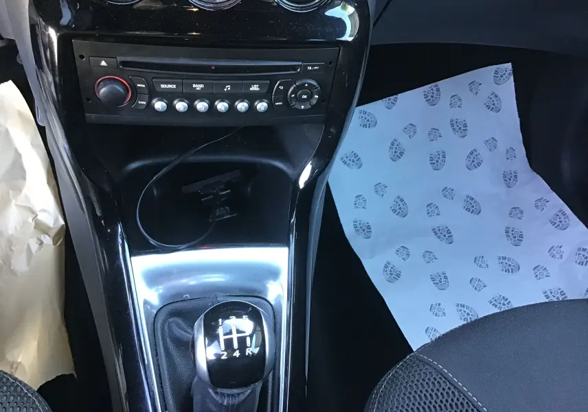 Vue rapprochée de la console centrale d'une Citroën DS3 gris clair, mettant en valeur le levier de vitesse manuel et la radio.