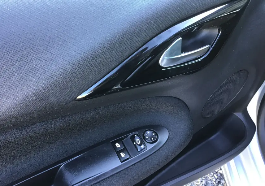 Gros plan sur la porte côté conducteur d'une Citroën DS3 gris clair, montrant la poignée intérieure et les commandes des vitres.