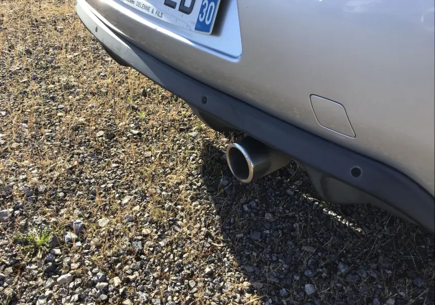 Gros plan sur l'arrière droit d'une Citroën DS3 gris clair métal, montrant le pare-chocs et la sortie d'échappement chromée.