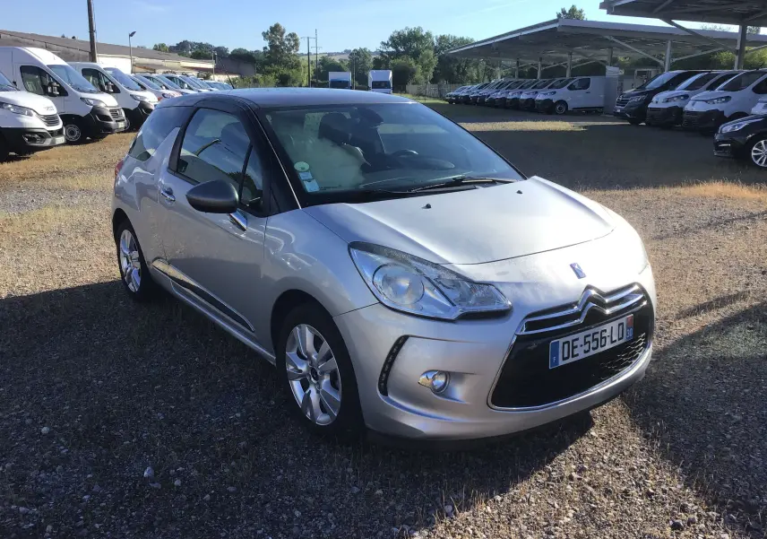 Citroën DS3 gris clair métal vue 3/4 avant droit, toit noir contrasté et jantes alliage 16 pouces sur parking extérieur.