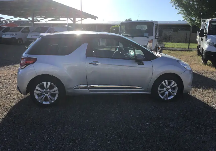 Vue de profil côté gauche d'une Citroën DS3 gris clair métal, avec jantes alliage et toit noir contrastant.