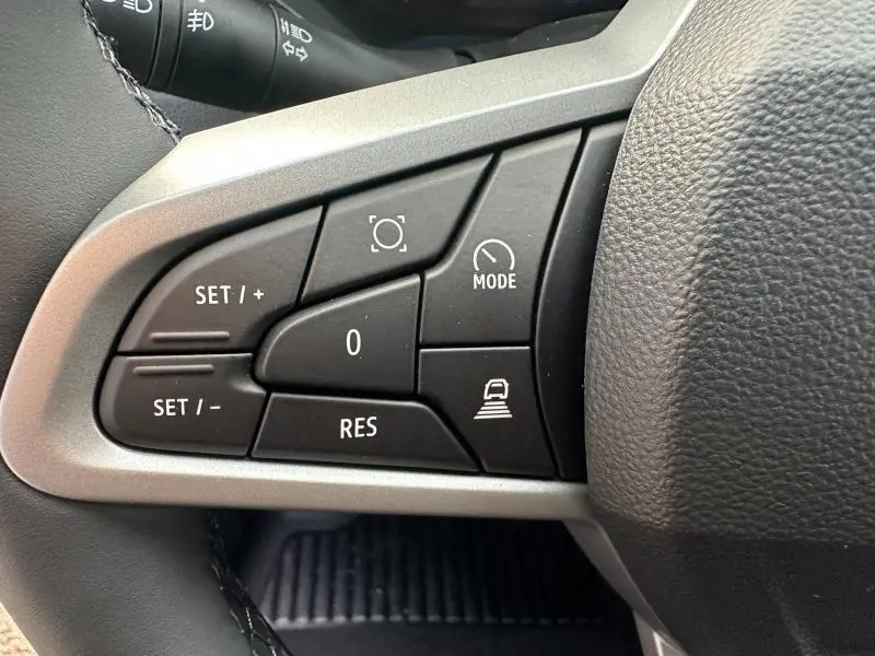 Gros plan sur les commandes de régulateur de vitesse au volant du Dacia Duster 2025, finition Noir Nacré métallisé.