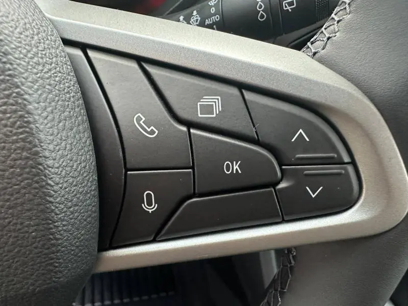 Gros plan sur les commandes multifonctions noires du volant du Dacia Duster 1.8 hybrid 2025, finition Journey.