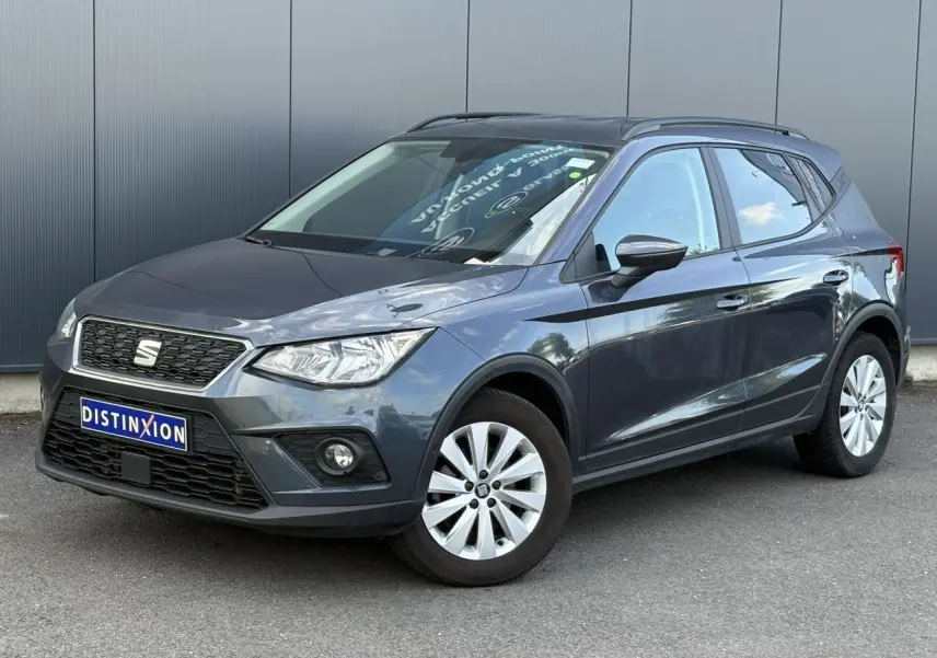 SEAT Arona gris magnétique en 3/4 avant droit, avec jantes alliage et calandre noire distinctive.