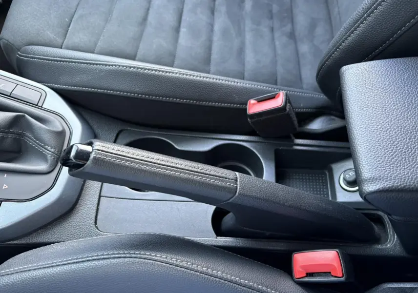 Vue rapprochée de la console centrale du SEAT Arona 2020, montrant frein à main cuir et sièges suédine gris.