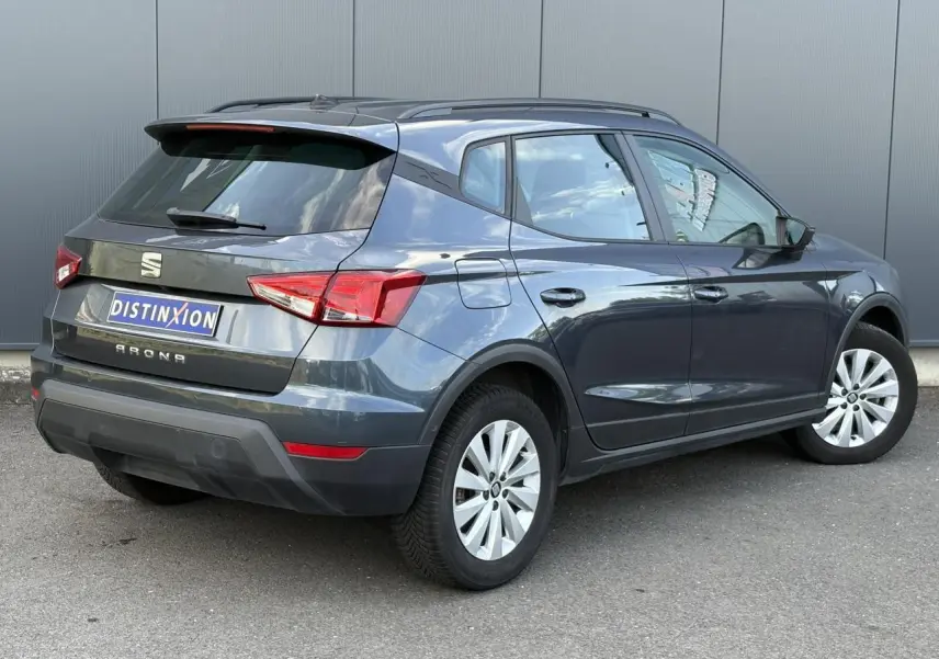 SEAT Arona TSI 110 DSG Style gris magnétique vu en 3/4 arrière droit, vitres teintées et jantes alliage visibles.
