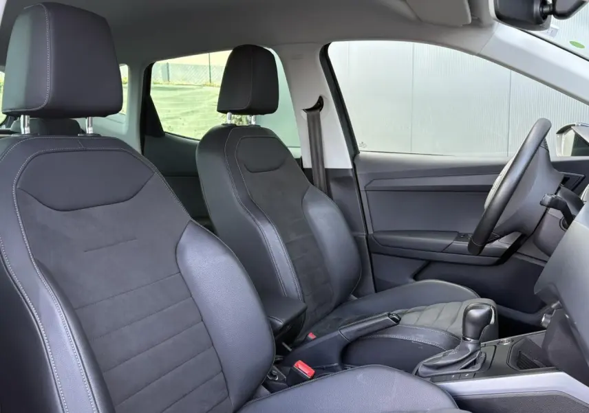 Vue intérieure côté conducteur du SEAT Arona 2020, sièges en suédine gris foncé avec console centrale et levier de vitesse automatique.