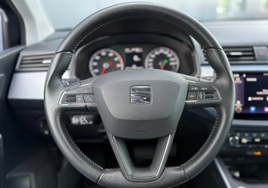 Volant en cuir noir de la SEAT Arona TSI 110 DSG Style 2020, avec commandes multifonctions et tableau de bord visible.