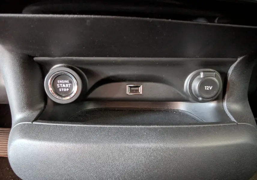 Gros plan sur la console centrale noire du Citroën C4 Cactus 2019, avec bouton start/stop et prise 12V visibles.