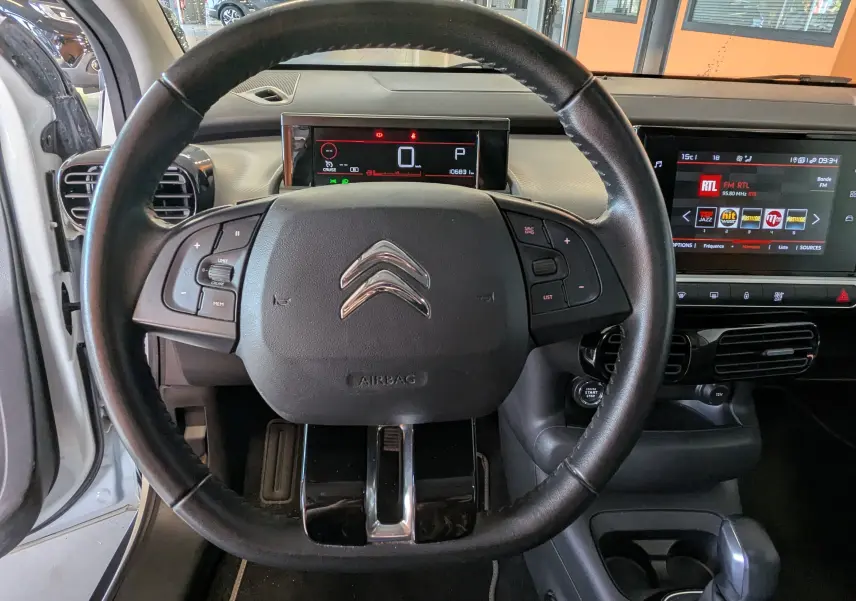 Vue intérieure centrée sur le volant noir de la Citroën C4 Cactus 2019 avec tableau de bord digital et écran tactile.