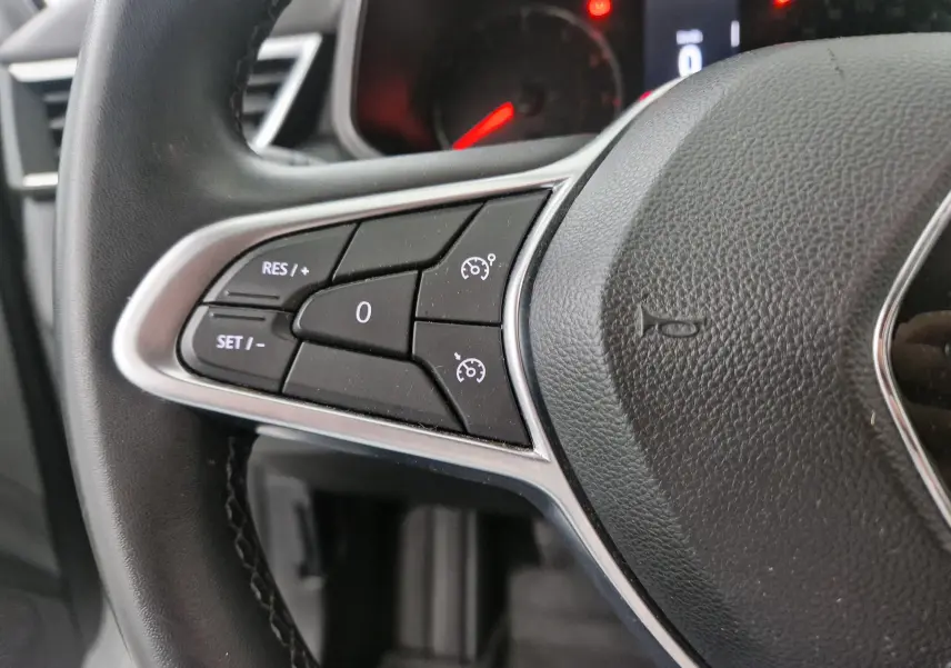 Gros plan sur les commandes de régulateur de vitesse au volant noir d'une Renault Clio V gris platine, 2021.