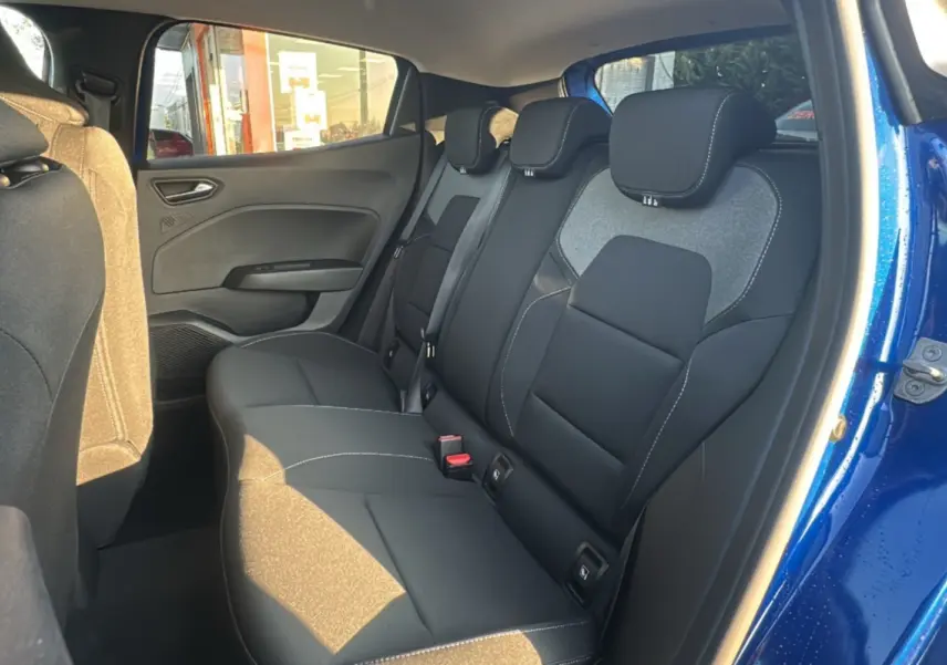 Vue intérieure arrière côté droit de la Renault Clio 2025 bleu iron, montrant les sièges arrière en tissu noir avec surpiqûres blanches.